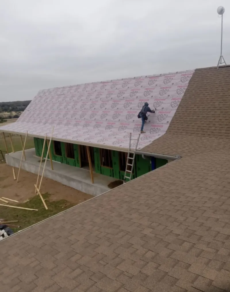 Worker preparing underlayment for a metal roof installation in Chelsea
